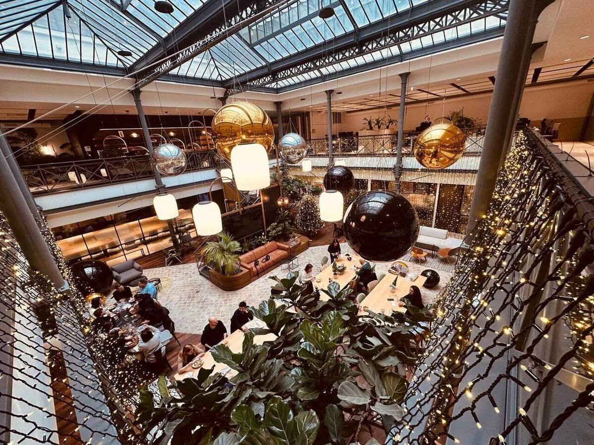 Ballons miroirs dorés, argentés et noirs suspendus dans un atrium