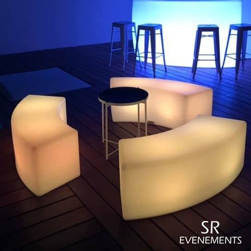 Bancs arrondis éclairés en ambre autour d’une table sur une terrasse