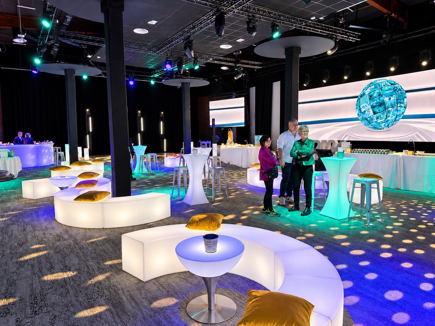 Bancs arrondis lumineux blancs autour de tables basses dans une salle sous un globe turquoise
