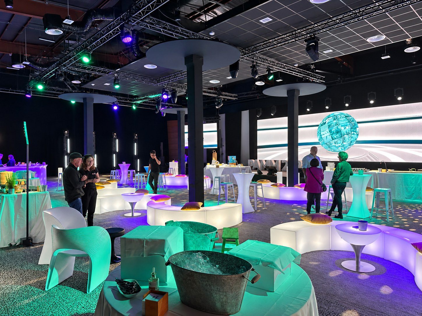 Bancs arrondis blancs avec coussins dorés et tables basses dans une salle de réception