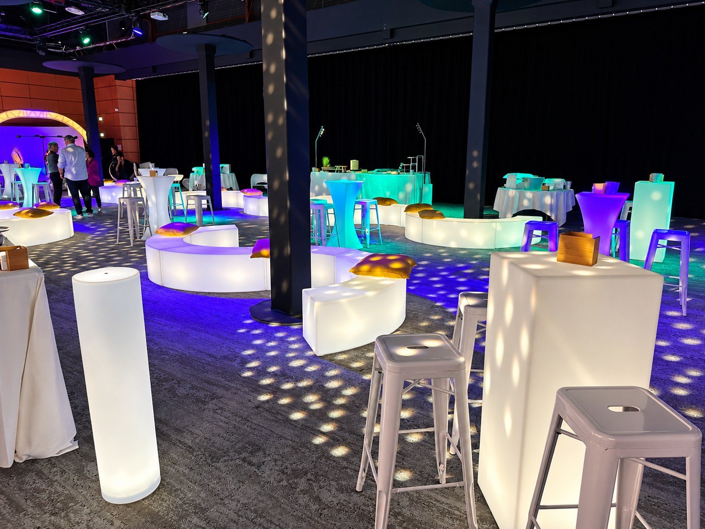 Bancs lumineux arrondis entre des mange-debout et des tabourets hauts en salle