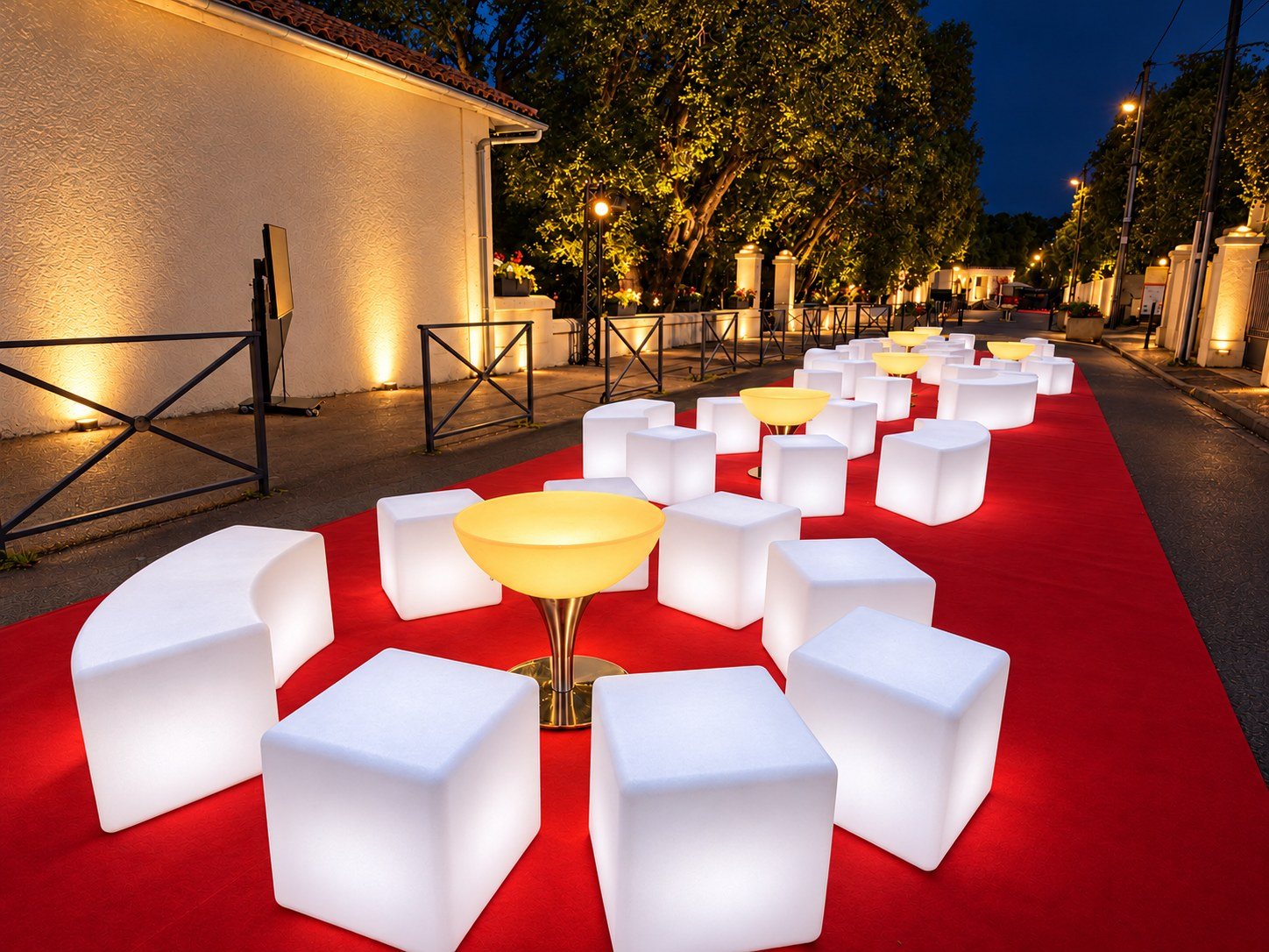 Une allée de salons avec bancs blancs, cubes et tables ambrées sur tapis rouge