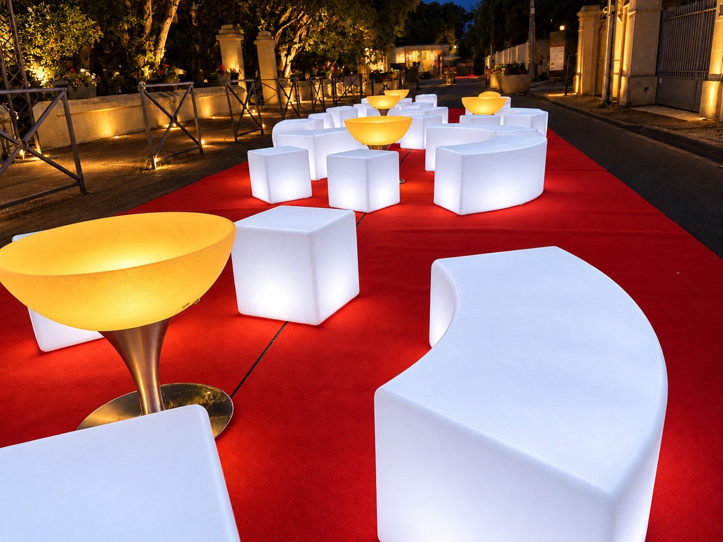 Détail du banc lumineux arrondi blanc près d’une table basse ambrée sur tapis rouge