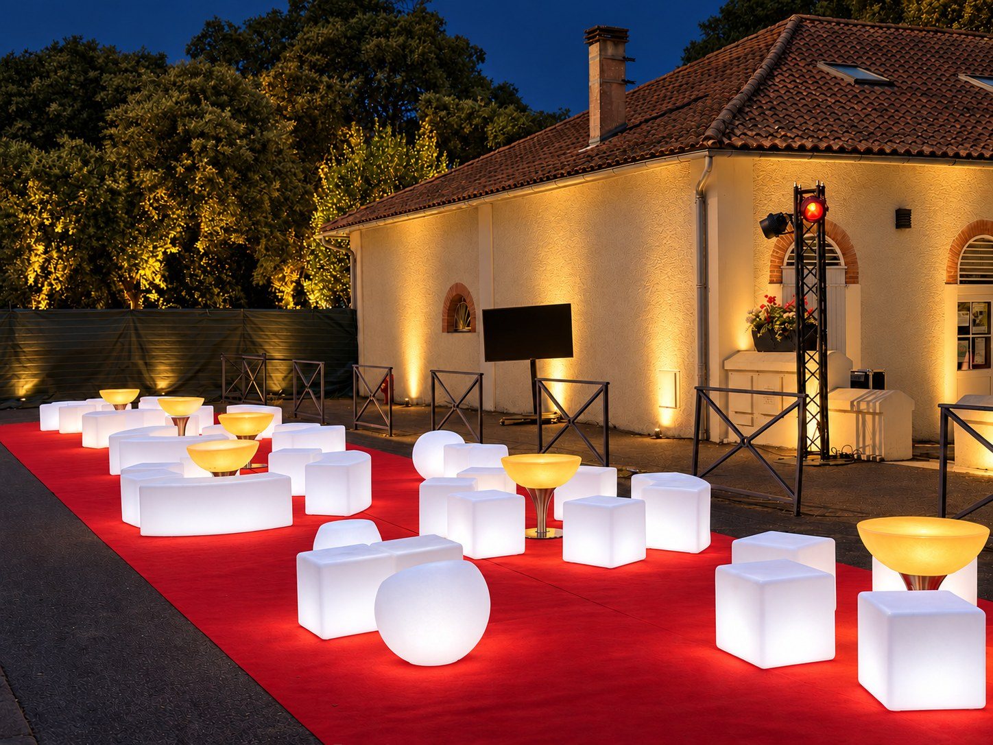 Bancs blancs lumineux et tables basses ambrées alignés sur un tapis rouge de nuit