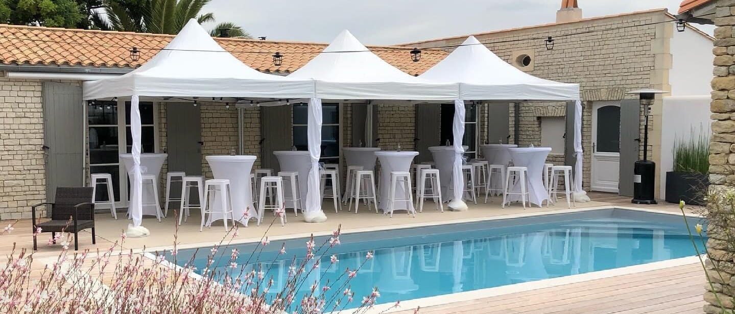 Barnums blancs avec mange-debout et tabourets autour d’une piscine