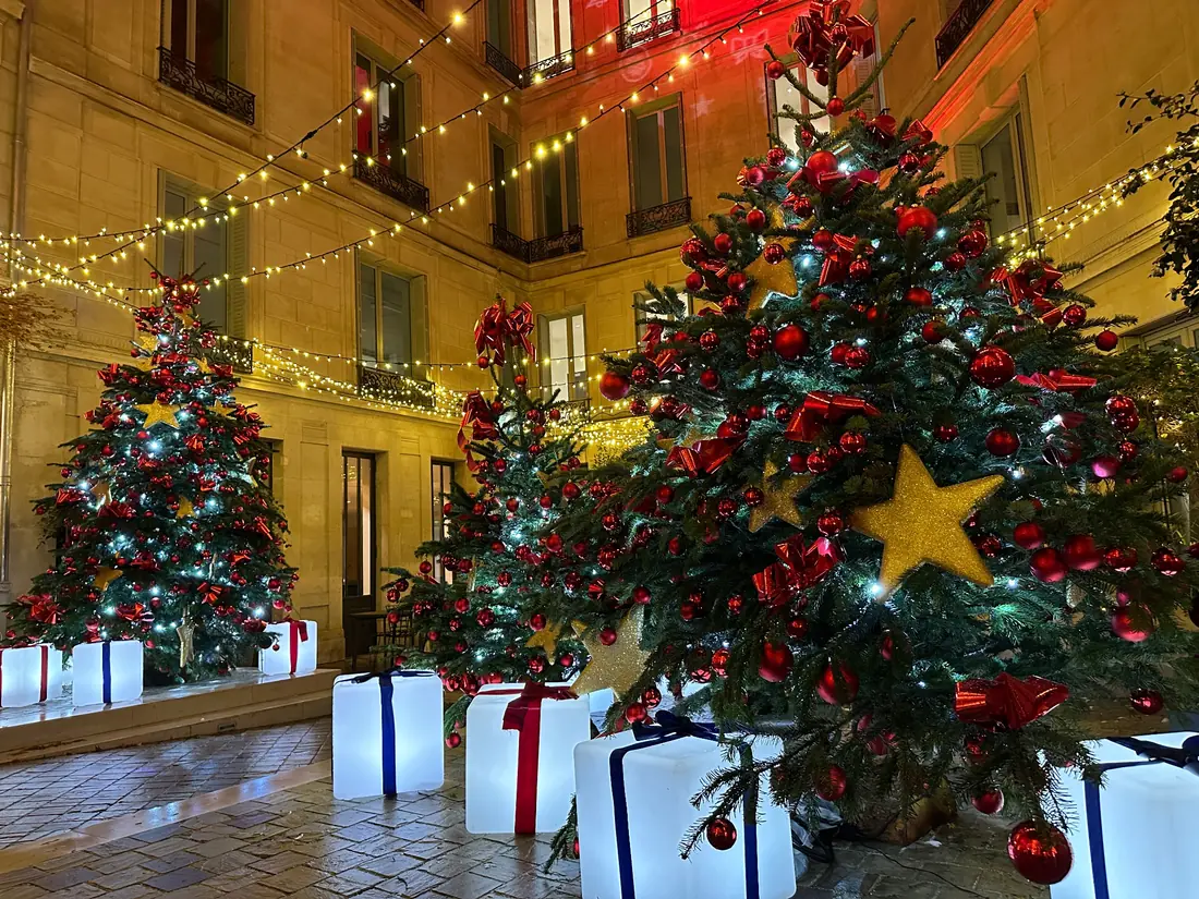 Cubes cadeaux lumineux installés dans une cour décorée pour Noël