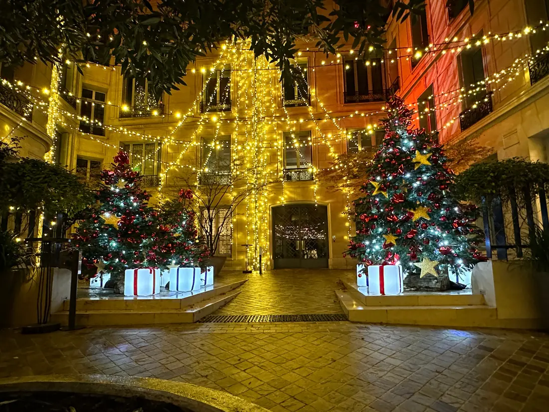 Vue centrale d’une cour de Noël décorée de sapins et cadeaux lumineux
