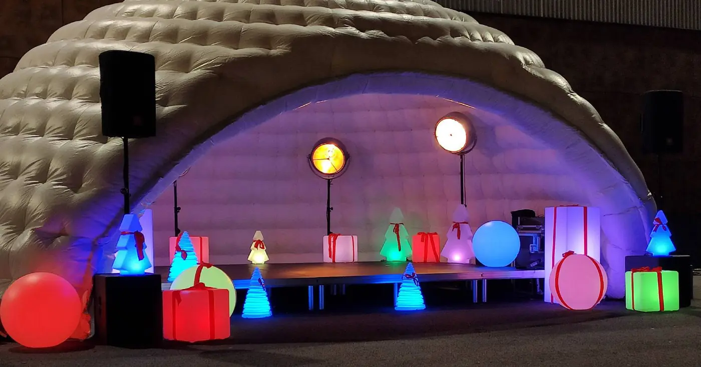 Décor de Noël avec cadeaux, sapins et sphères lumineuses devant un igloo événementiel