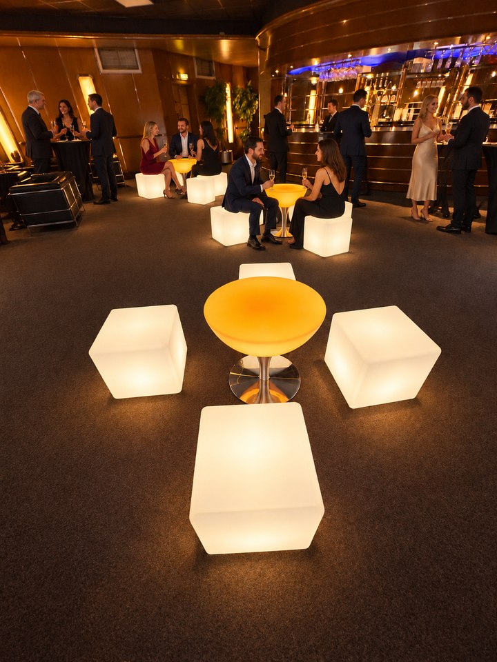 Cubes blancs autour d’une table lumineuse ambrée lors d’une réception