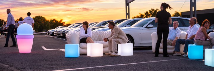 Cubes lumineux bleus et blancs devant des canapés lors d’une réception automobile