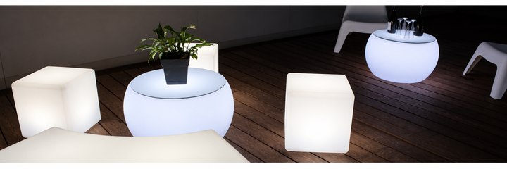 Cubes lumineux blancs associés à des tables basses rondes sur une terrasse