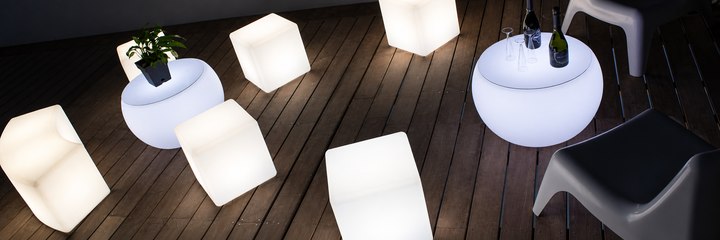 Cubes lumineux blancs et tables basses rondes vus du dessus sur une terrasse