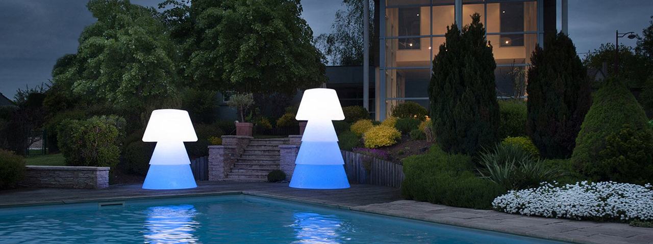 Deux lampadaires LED multicolores éclairés en blanc et bleu près d’une piscine