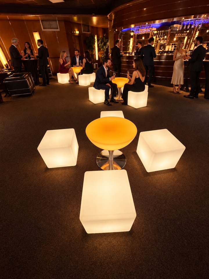 Table Lounge ambrée sur pied en inox avec trois cubes ivoire et invités en réception