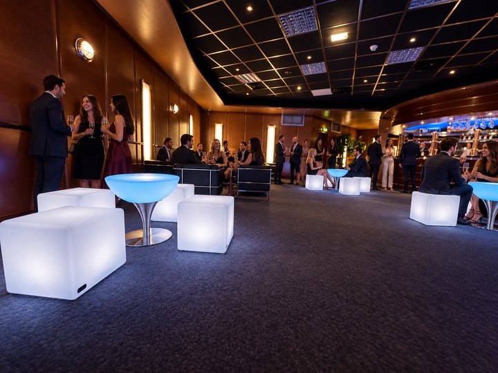 Table basse Lounge bleu glacier avec pied en inox et assises lumineuses dans une réception