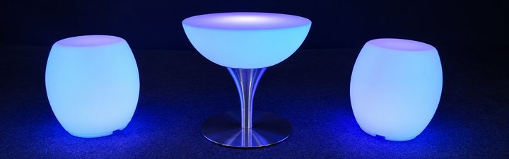 Table basse Lounge bleue sur pied en inox entre deux poufs lumineux