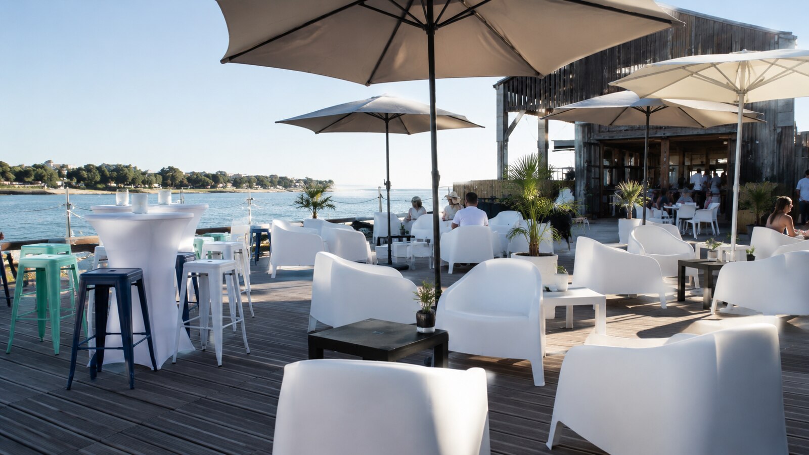Mange-debout blancs et salon lounge installés au bord de l’eau