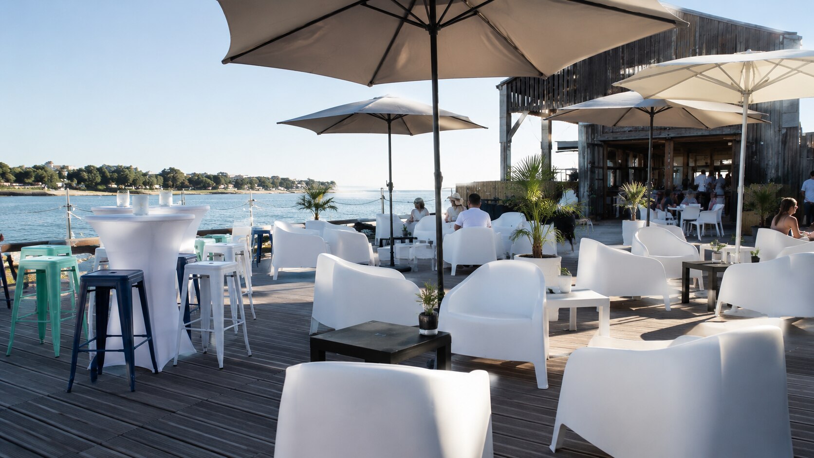 Fauteuils blancs et tables basses dans un espace lounge en bord de mer