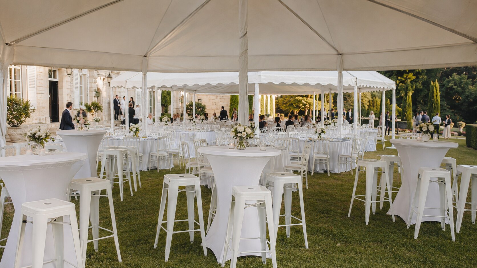 Tables, chaises et mange-debout blancs sous des tentes de réception