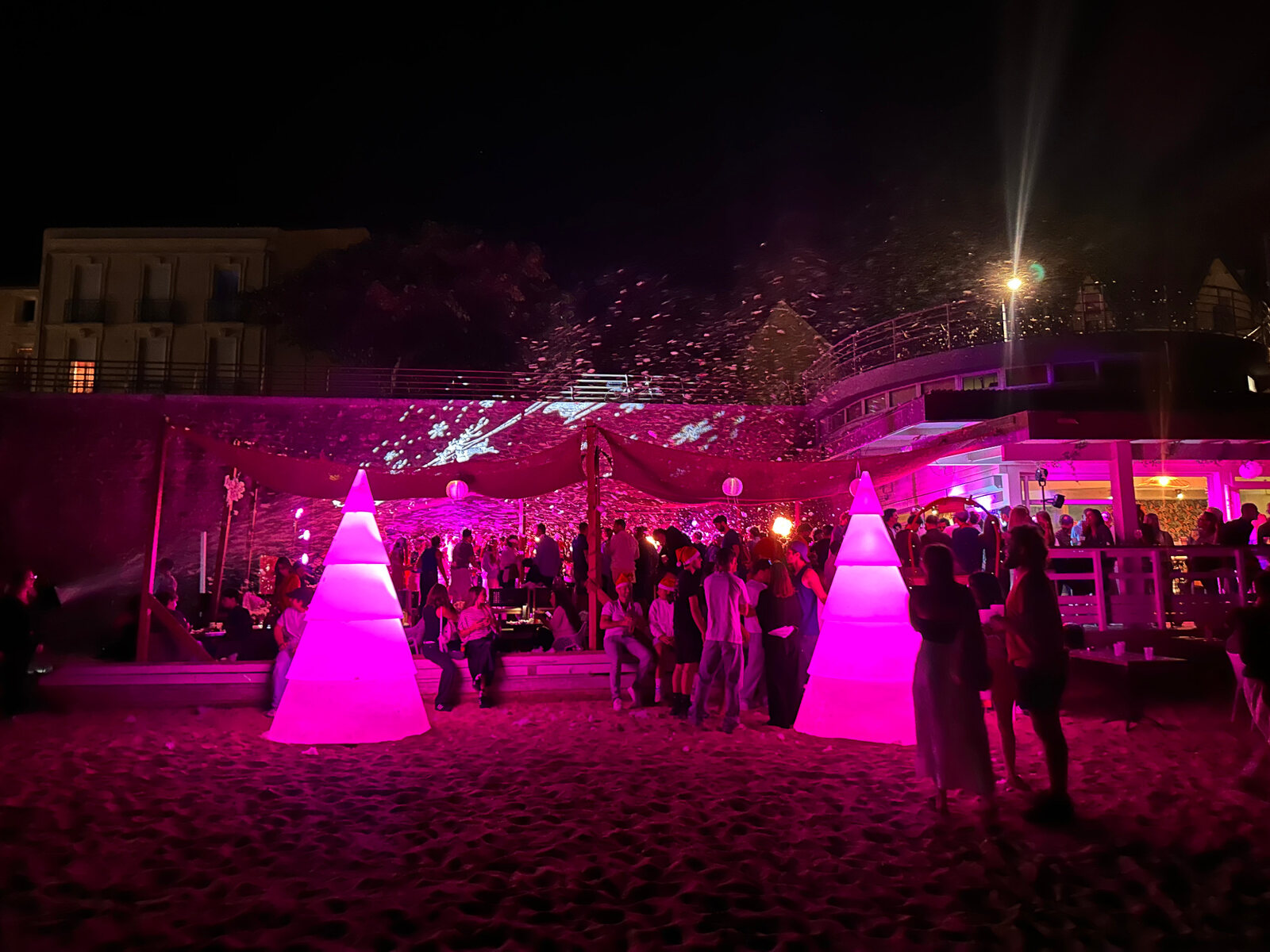 Grands sapins lumineux roses lors d’un événement sur la plage