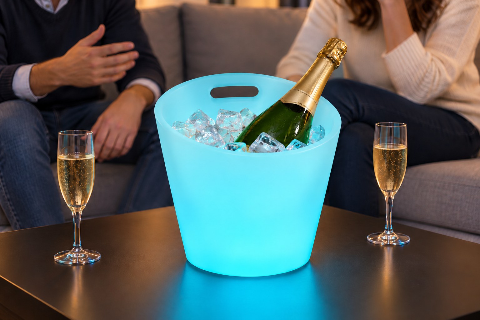 Seau lumineux à poignées cyan avec bouteille et glaçons devant un canapé