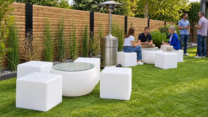 Tables basses et cubes blancs dans un jardin en journée, avec des invités à l’arrière-plan
