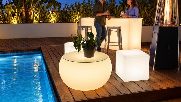 Vue détaillée d’une table basse ronde ambrée avec plateau en verre près de la piscine