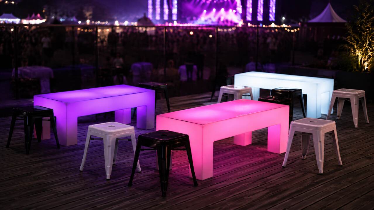 Tabourets bas acier noirs et blancs avec tables lumineuses pendant un festival