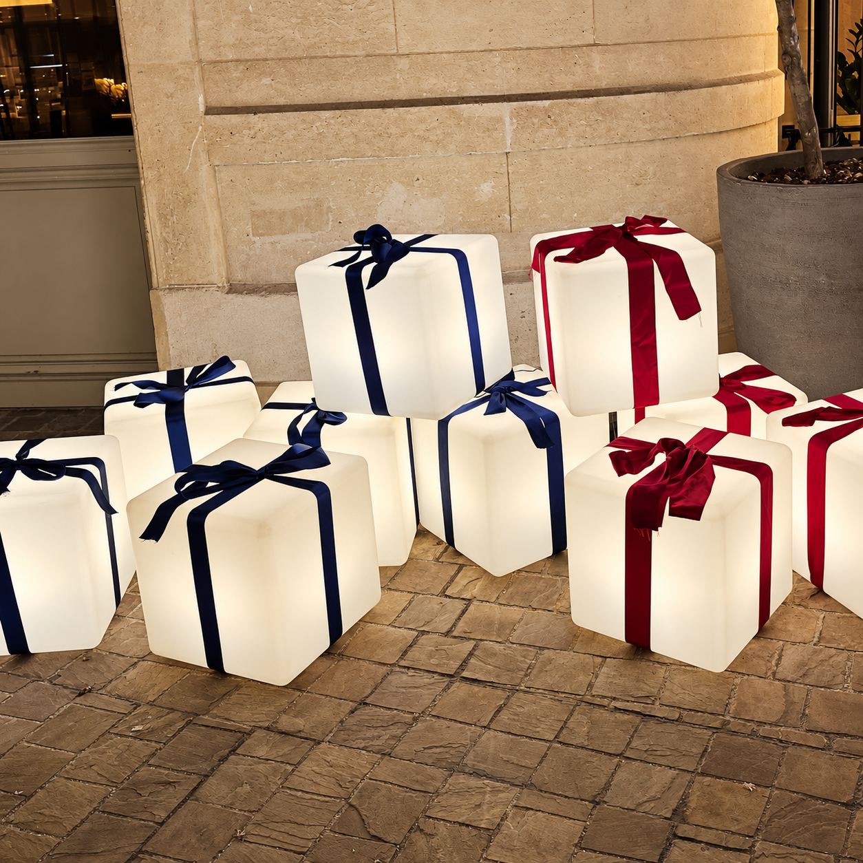 Cadeaux lumineux blancs avec rubans rouges et bleus dans une cour